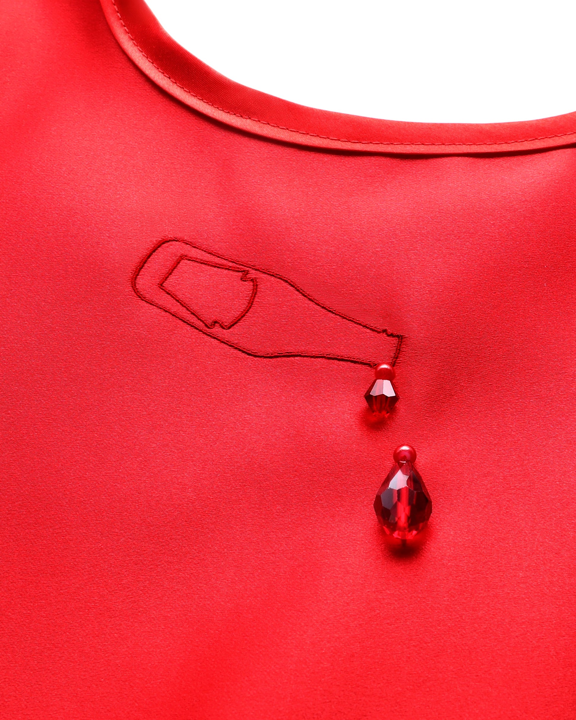 A close-up of a bright red bib featuring an embroidered outline of a teardrop-shaped bottle with two faceted red teardrop gems hanging below it.